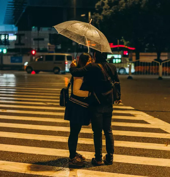 街头相互遮风挡雨的一对情侣. (来自:腾讯大申网)