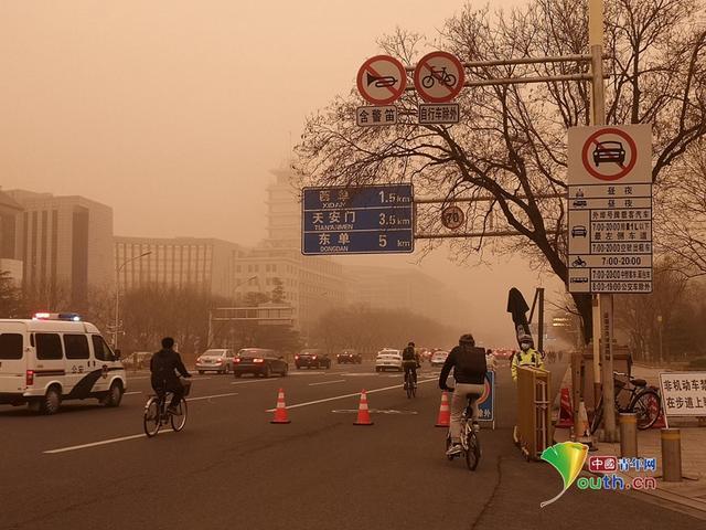 3月15日早晨,北京城区遭遇沙尘天气,空气质量和能见度降低,市民在土