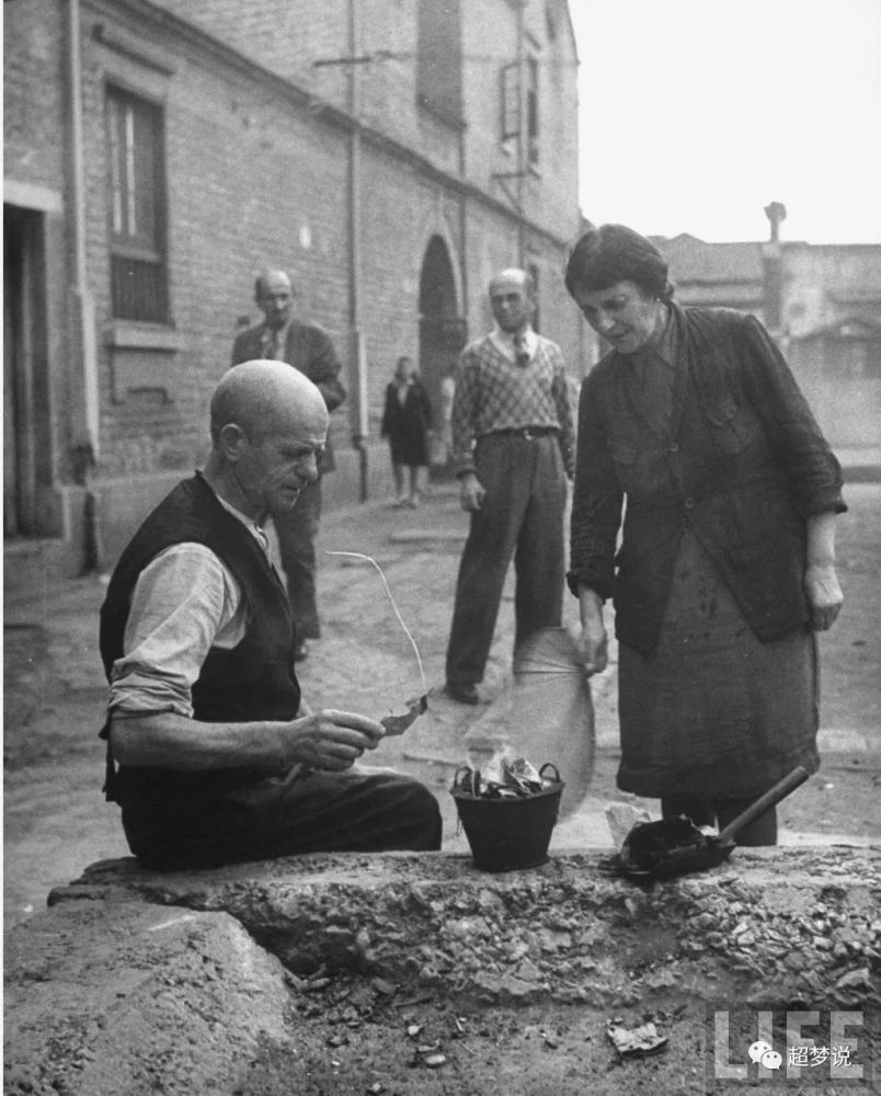 1945年11月,中国上海seward路犹太区,犹太妇女试着用中国蒲扇生火