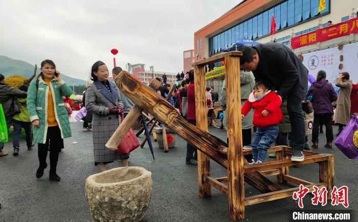 广西灌阳"二月八"农具节上,游客在舂米碓上玩耍.