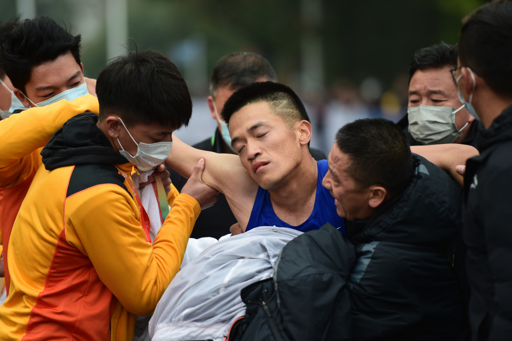 3月21日,山东队选手边通达(中)通过终点后体力不支被搀扶离场.