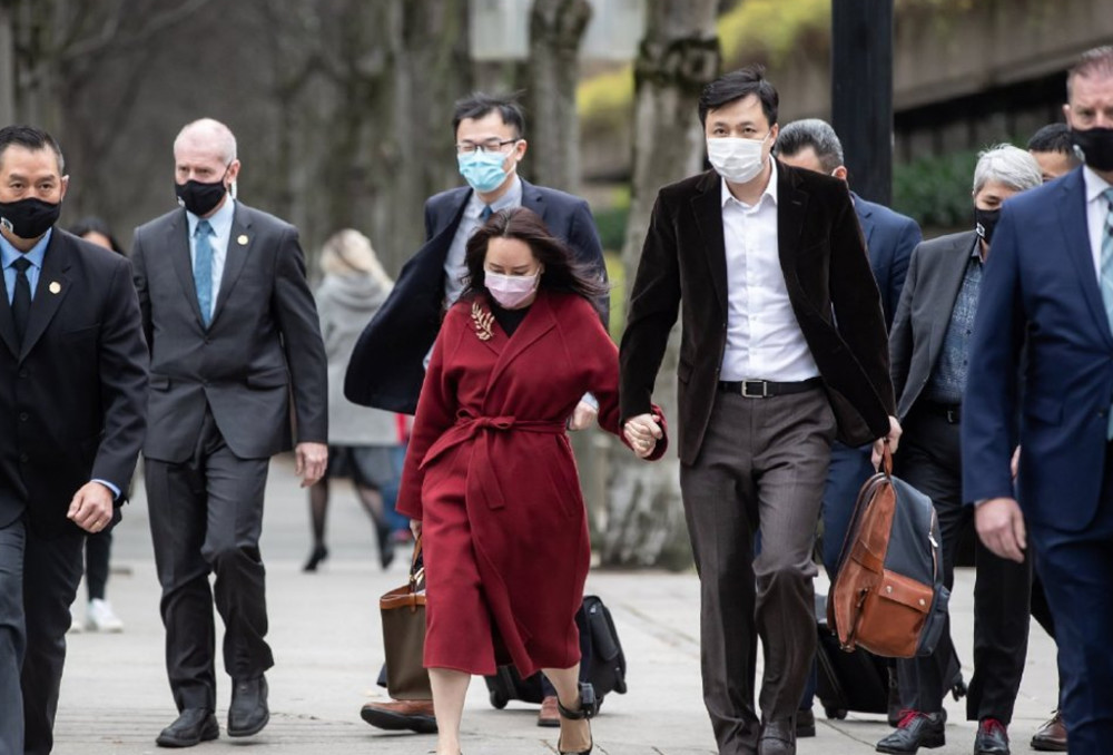 孟晚舟光腿穿棕红色大衣,搭配黑色高跟鞋,气场与气质兼顾,腰部的腰带