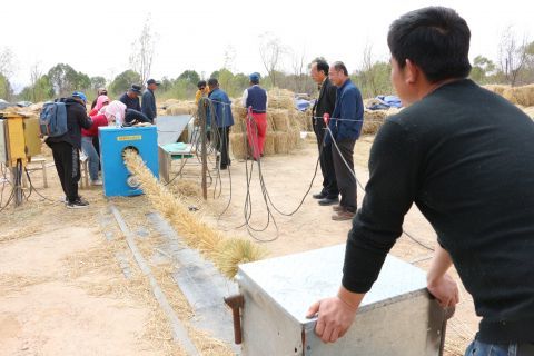 在中卫治沙林场,工人们利用草方格沙障材料专用生产装置(机器)将提前