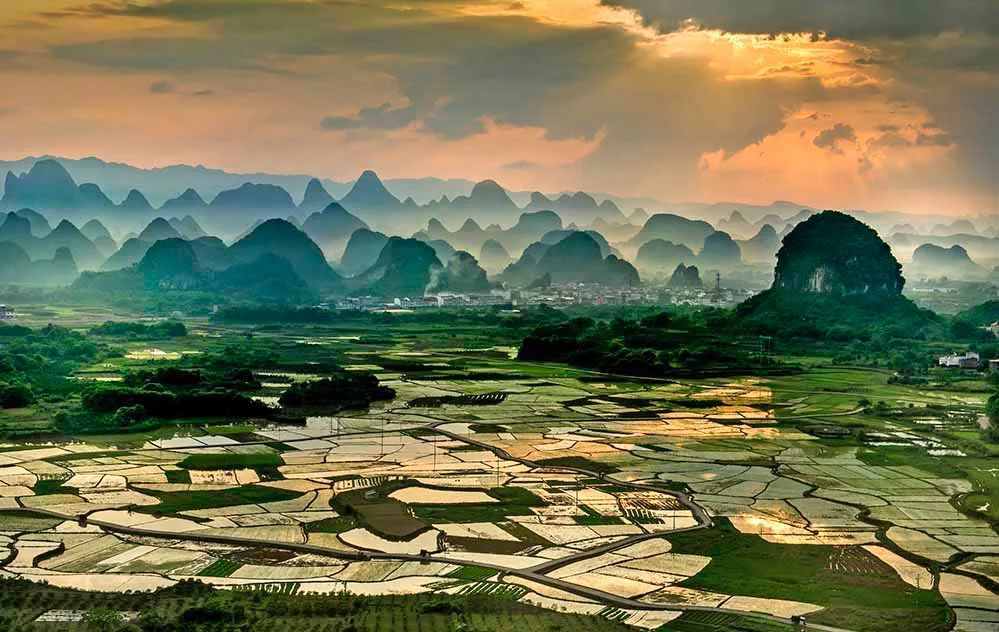 每年7,8月份,荷花盛开,满满一塘,不远处的峰林高高耸立,云遮雾绕,宛如