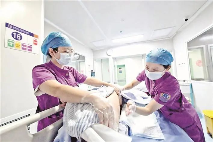 宝安区中心医院icu里,两位护士正在帮病人翻身拍背.