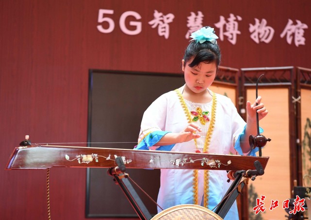 身着京族传统服饰的许艺在弹拨独弦琴,展现非遗技艺.
