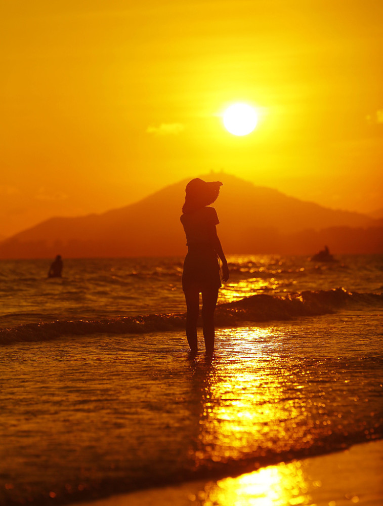 海南三亚:游人海边夕阳中游玩赏景