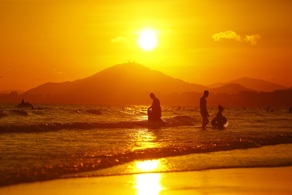 海南三亚:游人海边夕阳中游玩赏景