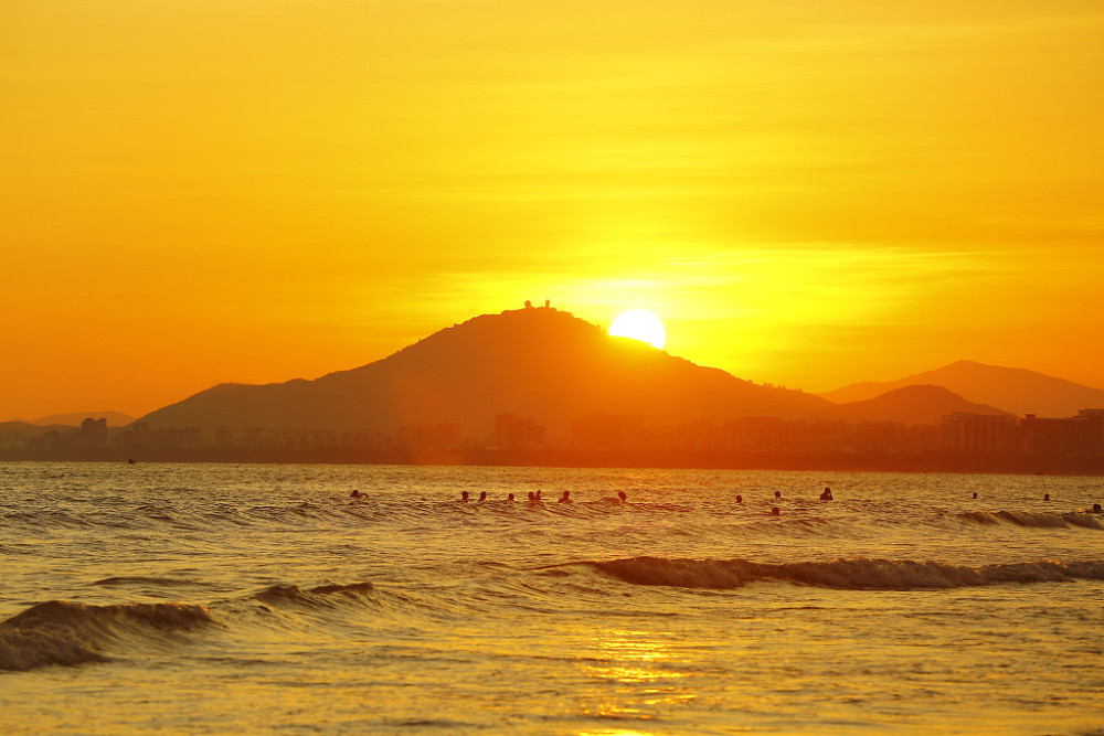 海南三亚:游人海边夕阳中游玩赏景