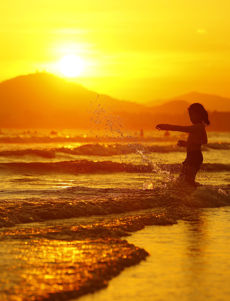 海南三亚:游人海边夕阳中游玩赏景