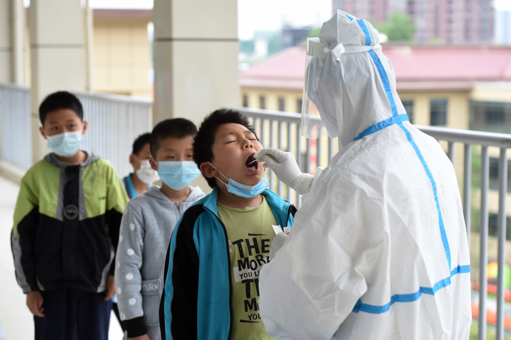 5月17日,在六安市清水河学校第二小学,检测人员登记做核酸检测的学生