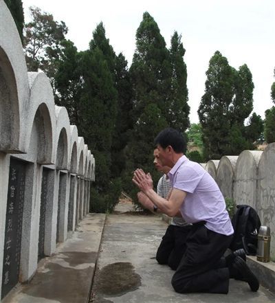 郑大臣和儿子郑晓来跪在郑臣旺的墓碑前祭拜.图据盐边县融媒体中心