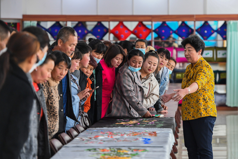 3月23日,曹峰在家中指导妻子包风艳刺绣.新华社记者 刘磊 摄