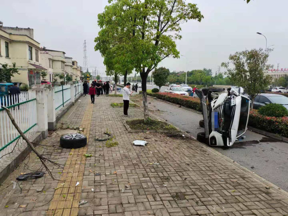 姜堰陈庄路石家岱小区门前发生一起交通事故,一辆白色轿车飞越路边