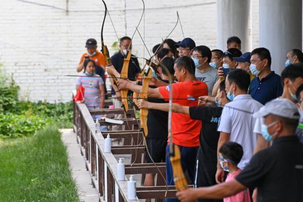 5月29日,在察布查尔锡伯自治县锡伯古城景区,当地居民和游客体验射箭.