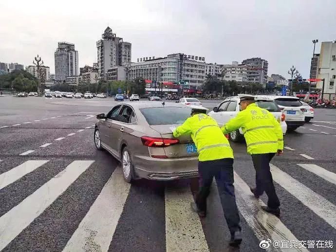 在路中央 正好高考考生的车辆即将出发,宜宾交警合力推车保证道路通畅