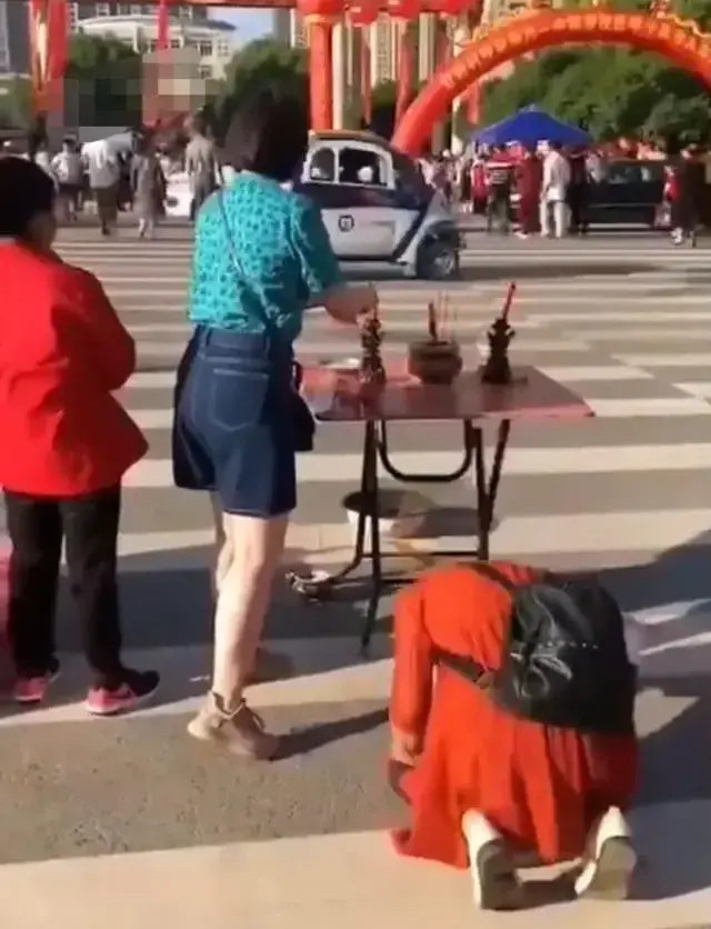 一位考生的妈妈正在上香,另一位考生的妈妈跪在地上磕头