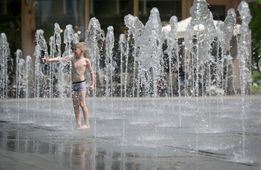 6月15日,一名儿童在俄罗斯莫斯科的一处喷泉戏水纳凉.新华社/法新