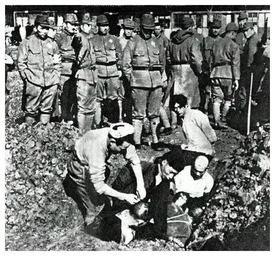 一群日本侵略者正在围观坑杀几名中国百姓的画面,照片中这些日本侵略
