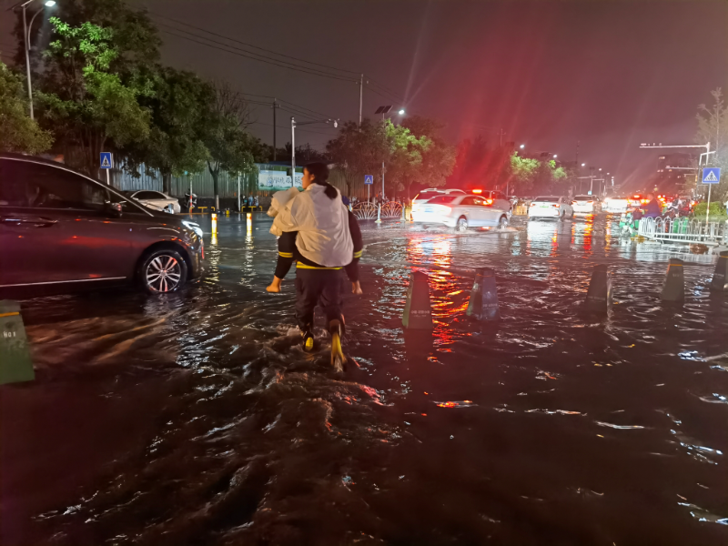 昨晚北京大雨有车遇积水,消防员背起老人孩子过马路