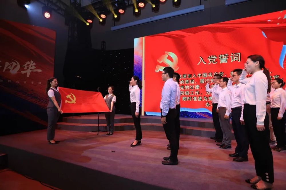一批新党员面向党旗, 在活动现场进行庄严宣誓.
