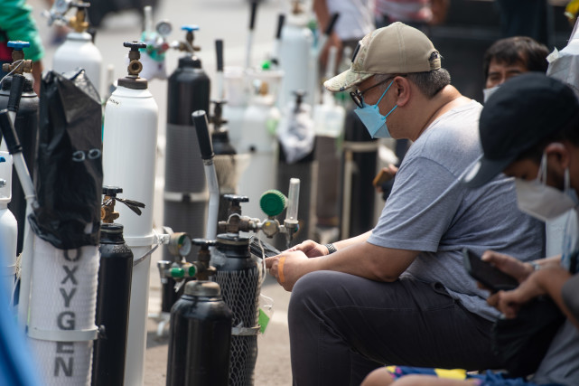 7月5日,一名男子在印度尼西亚雅加达拖着氧气罐去充氧.