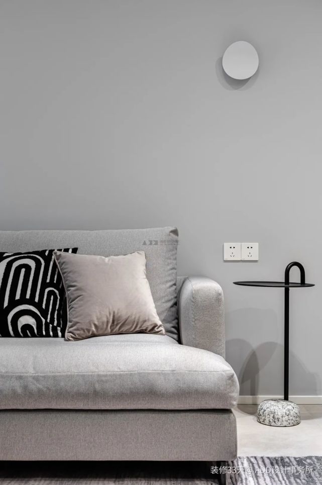 大面积的灰色墙面搭配浅灰色地毯和沙发,深棕色单椅和圆形石面茶几