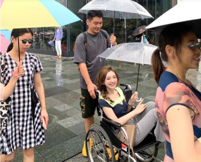 网红覃美莹作秀雨天坐轮椅出行称脚有洁癖晒美照却光脚踩马路
