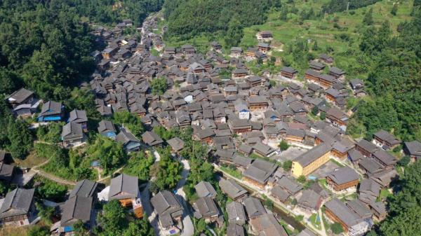 7月16日,一名游客在榕江县栽麻镇大利侗寨溪水边拍照游玩.