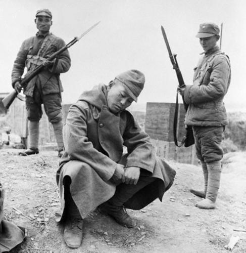 这日本俘虏还一脸的不服啊,这风衣似乎带兜帽,可能还是个宪兵
