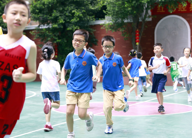 7月19日,小学生在广州小北路小学上篮球课前做热身运动.