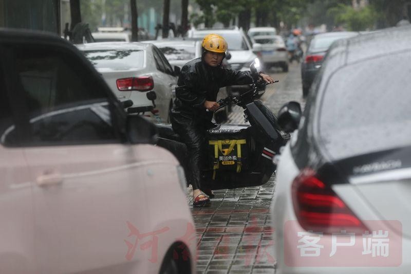 郑州街头外卖小哥冒雨送餐.