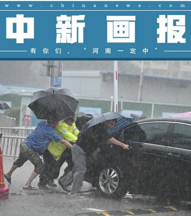 图为郑州火车站,暴雨中众人推车.图片来源:视觉中国