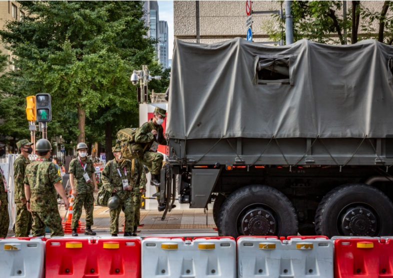 上图是日本自卫队某部在东京国立竞技场附近登上一辆军用卡车,准备到