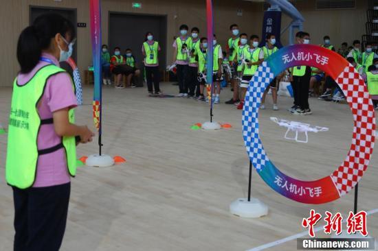 一名女学生正在操控无人机穿越障碍圆环.