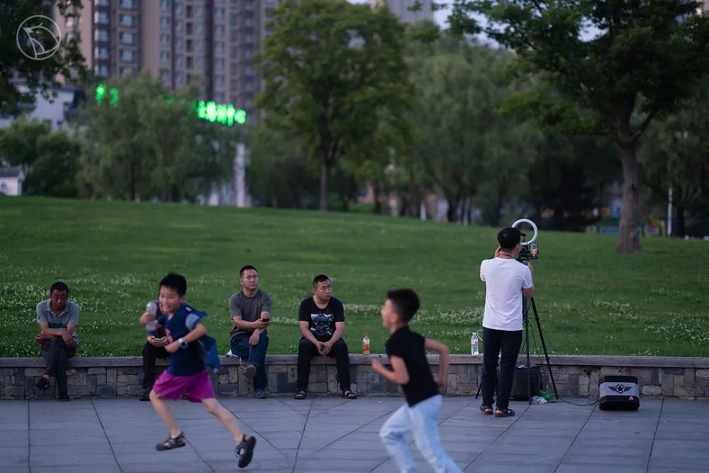 天水湖公园,做网络直播的主播身后,几名小孩嬉戏追逐