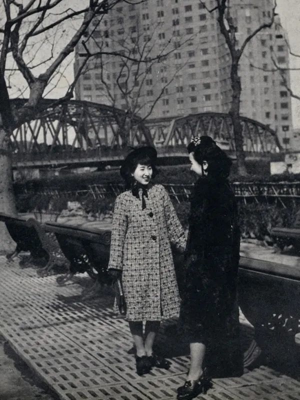 女性头戴时尚礼帽,手拿手包,脚穿黑色高跟皮鞋,尽管在当时中国最时尚