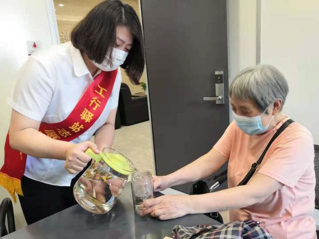 网点理财经理为到店的老年客户倒上降暑茶.任杨勤 摄