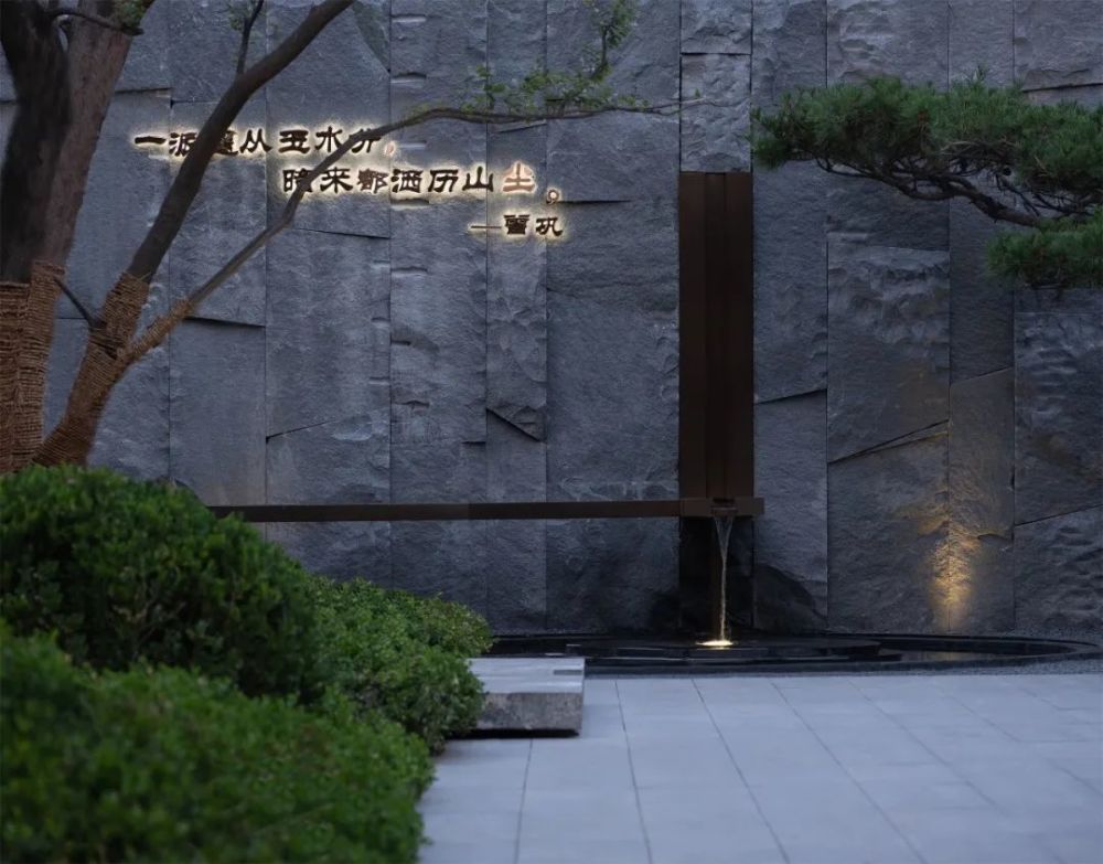 乔木映衬的步道的尽头是层次丰富的景墙对景