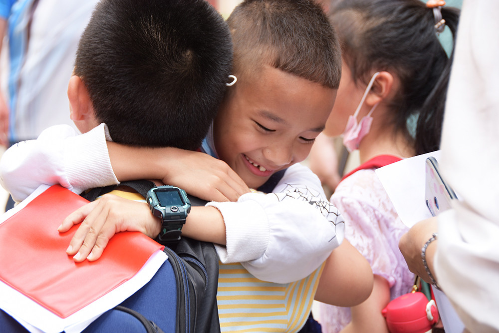 在云南省红河哈尼族彝族自治州个旧市绿春小学,一名小学生与同学拥抱
