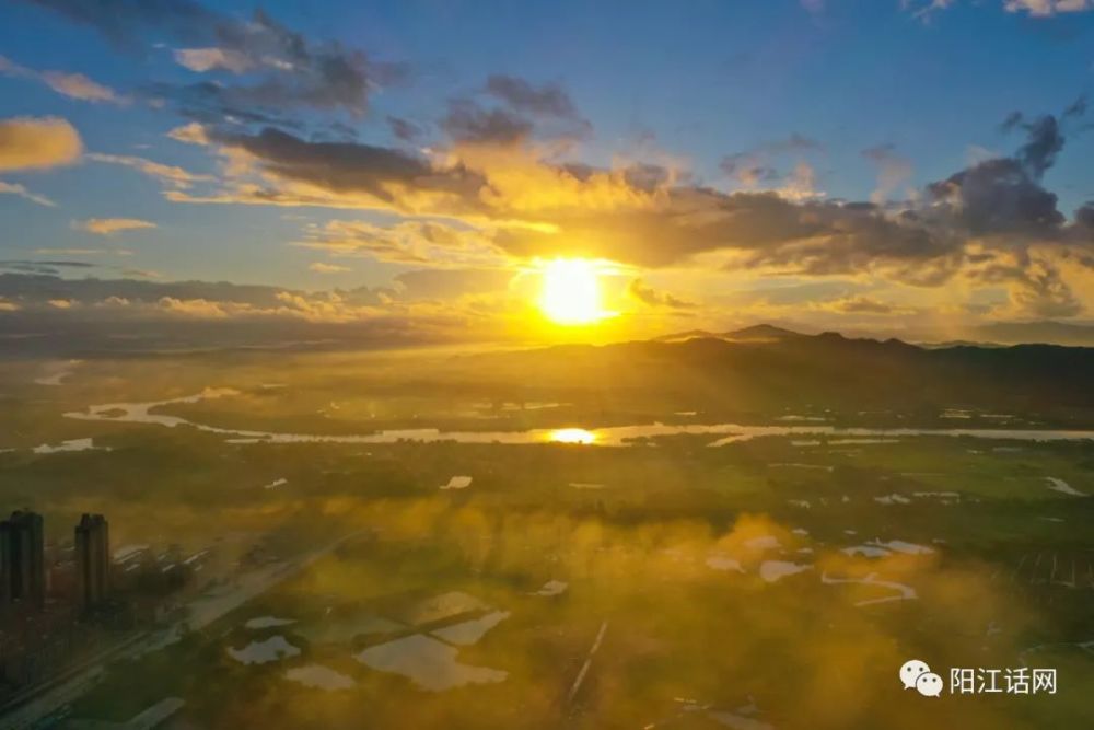 太阳终于跳出来了! 阳光透过层层云朵, 霞光万道, 普照大地.