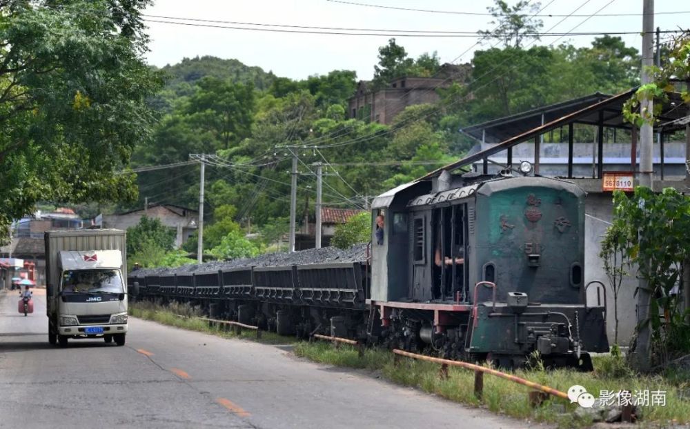 窄轨火车满载着原煤经过矿区居民区.