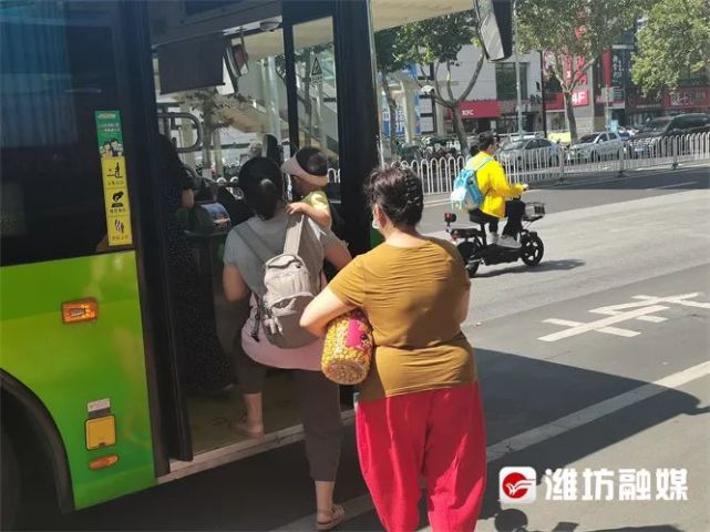 东风东街与新华路东南角公交站点,市民排队上车.