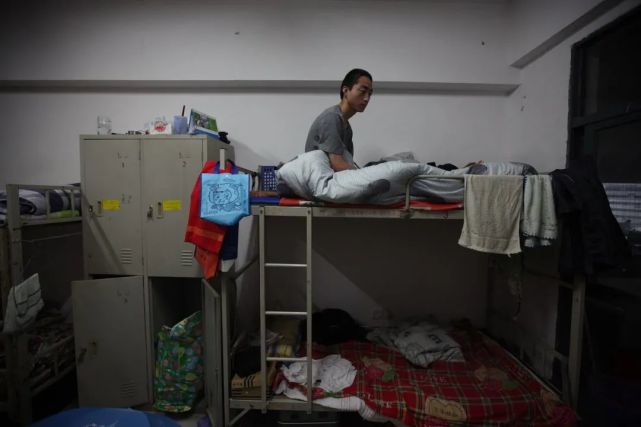 富士康员工宿舍内,一名男性员工坐在床上发呆.图 / 视觉中国