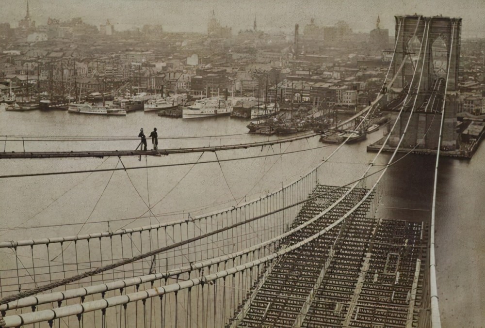 1880年,快完工的布鲁克林大桥,两位工人行走在施工桥上.