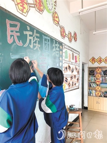 越华中学学生在制作民族团结主题黑板报.