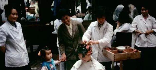 80年代老照片:一位女子正在烫头发,并且旁边有很多人正在围观,在当时