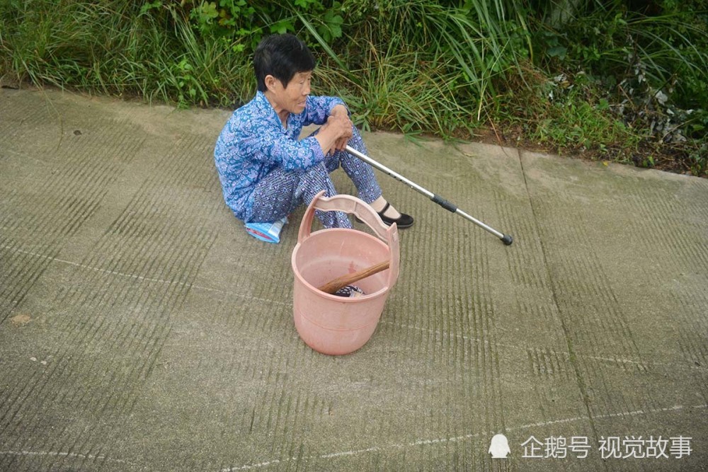 看到老人坐在地上歇息,有人准备帮奶奶把装衣服的桶提回去.