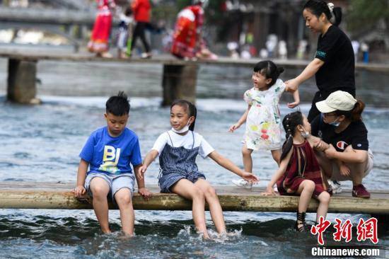 孩子们坐在木桥上戏水纳凉.