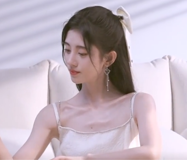 未修花絮中的鞠婧祎身着白色的吊带连衣裙,扎着半丸子公主头,加上一个